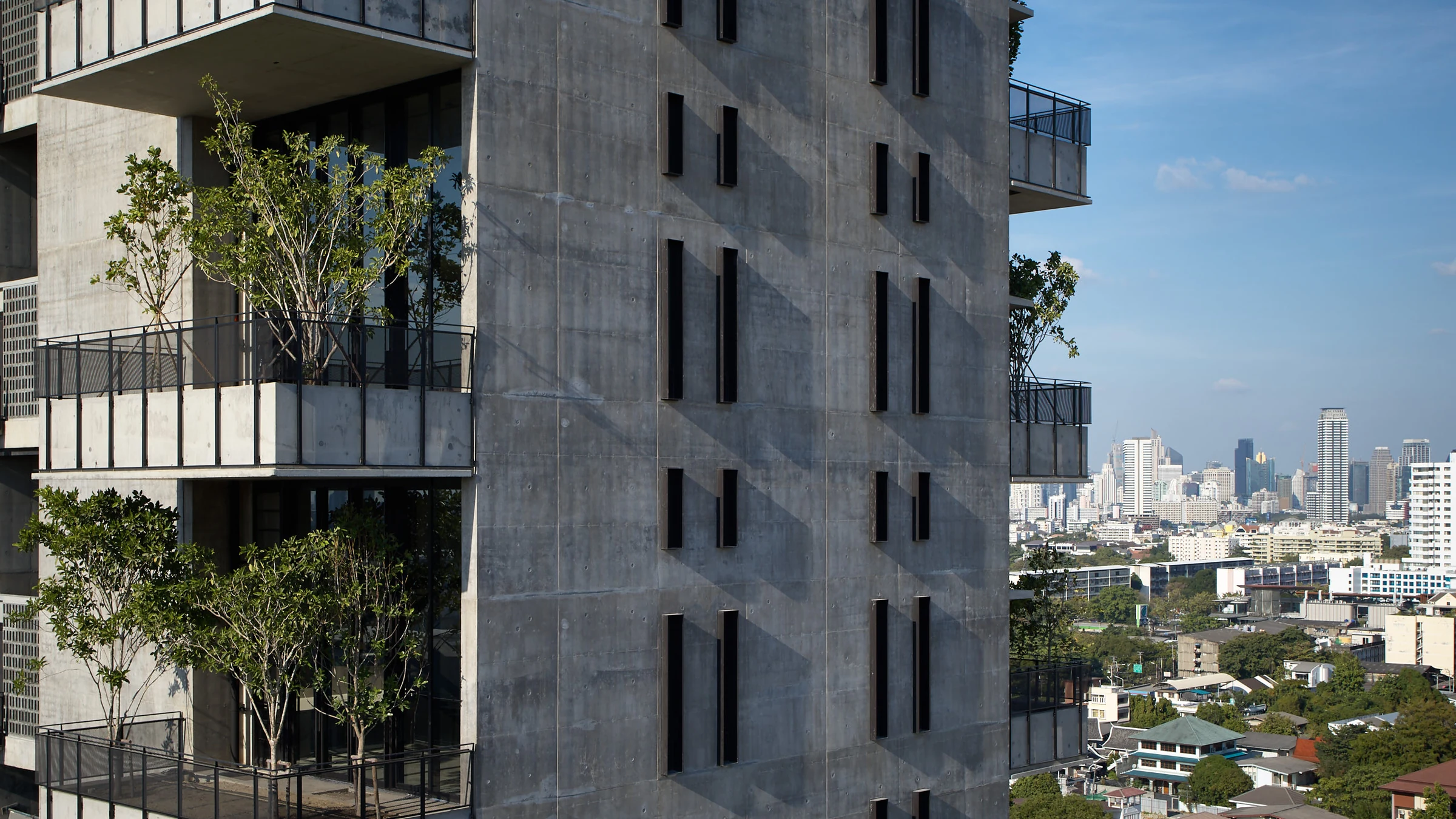 A residential facade with planted balconies overlooking the city.