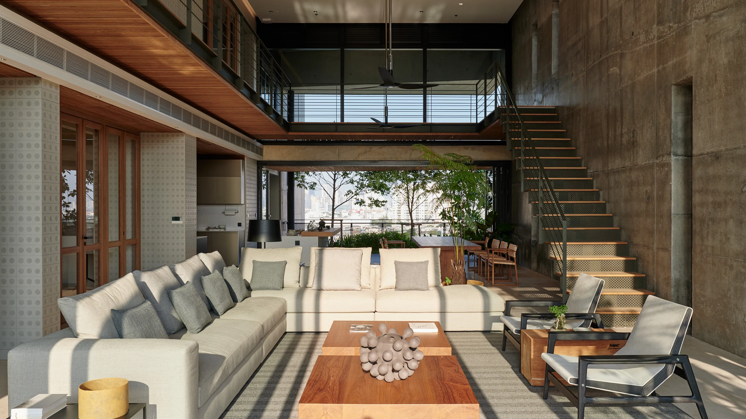 A double-height residence living room with a staircase and large windows.