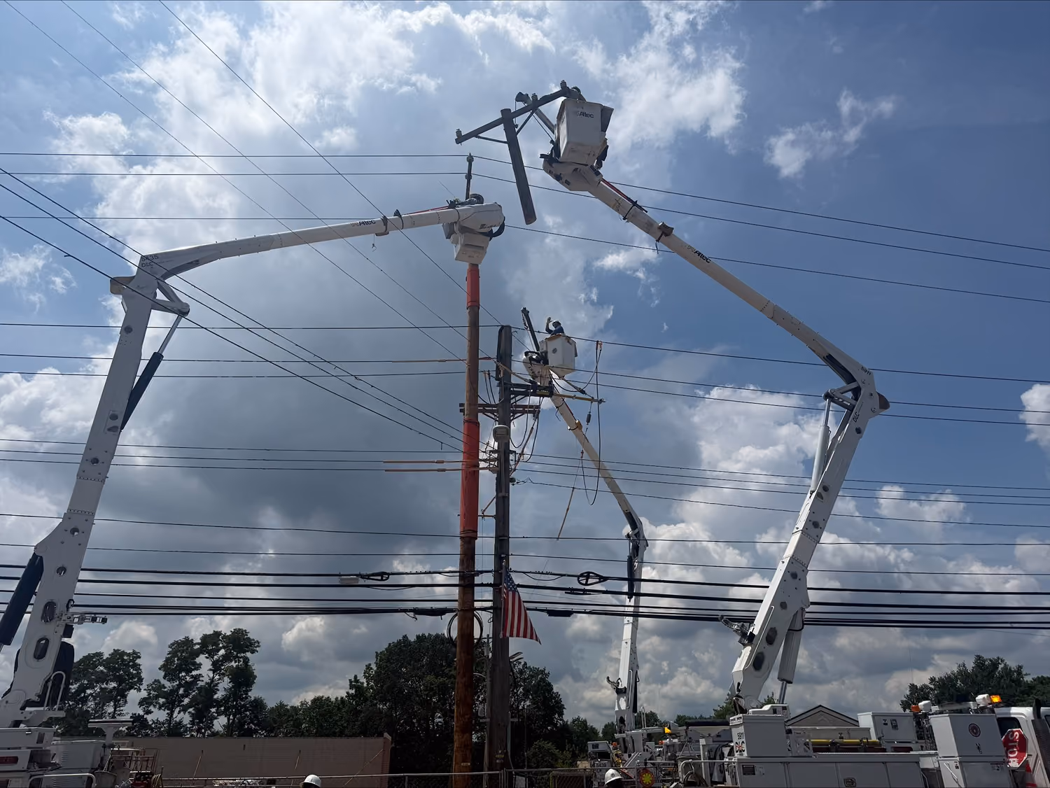IBEW Local 29 linemen in bucket trucks working on power lines against a cloudy sky