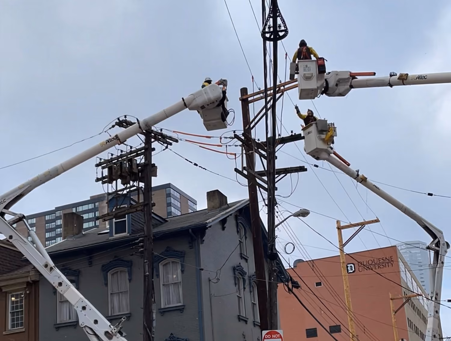 IBEW Local 29 linemen in bucket trucks working on power lines near a building