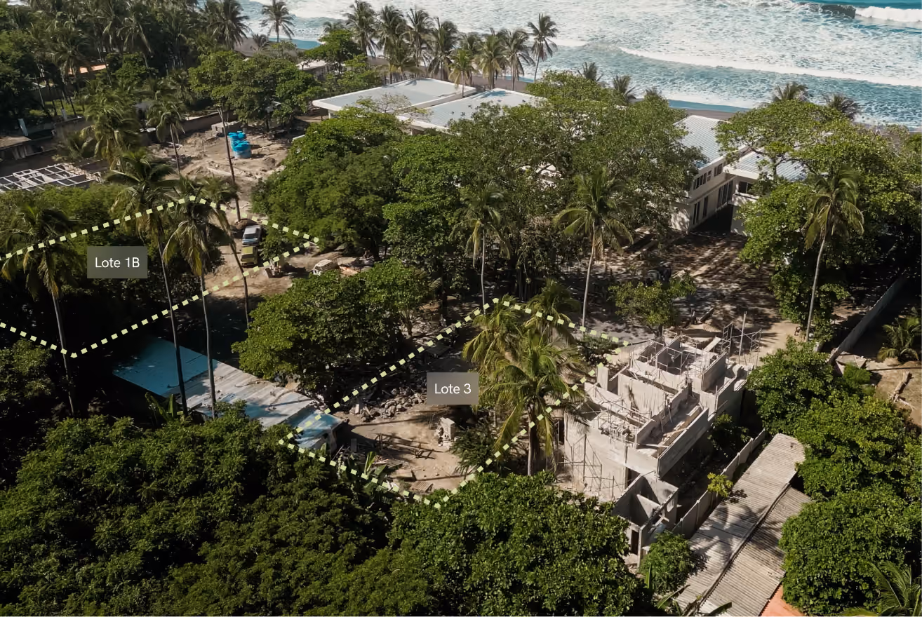Aerial view of tropical lots labeled Lote 1B and Lote 3 with trees, buildings, and ocean waves in the background.