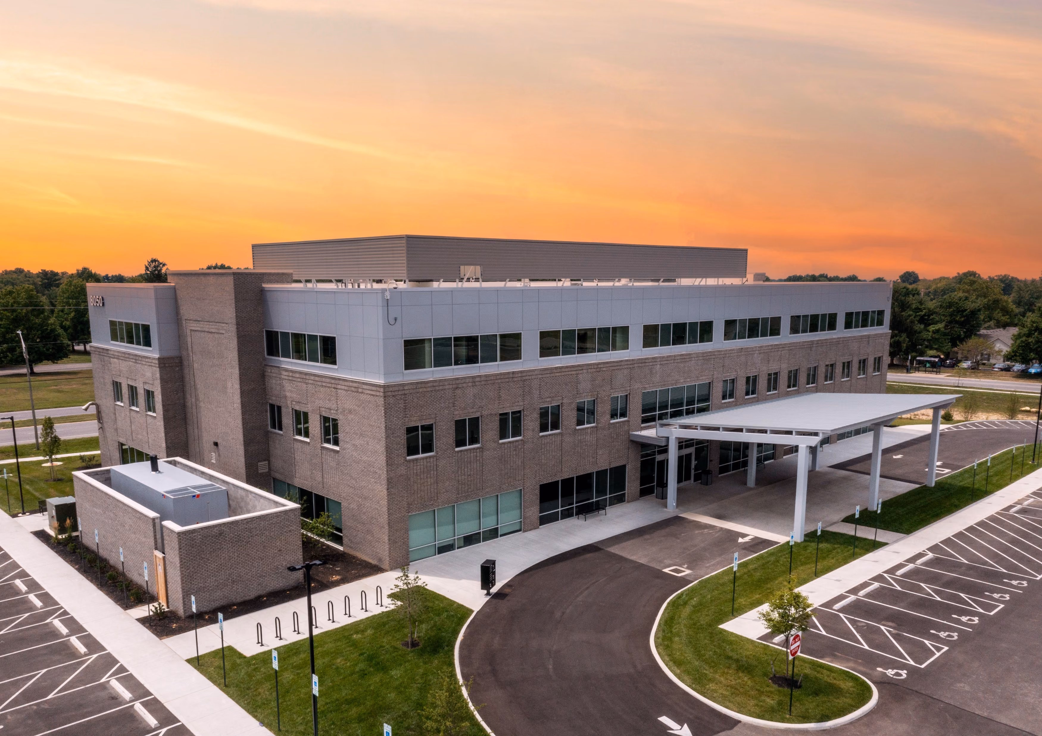 Three-story modern medical office building in Columbus, OH with brick and glass facade at sunset and empty parking lot.
