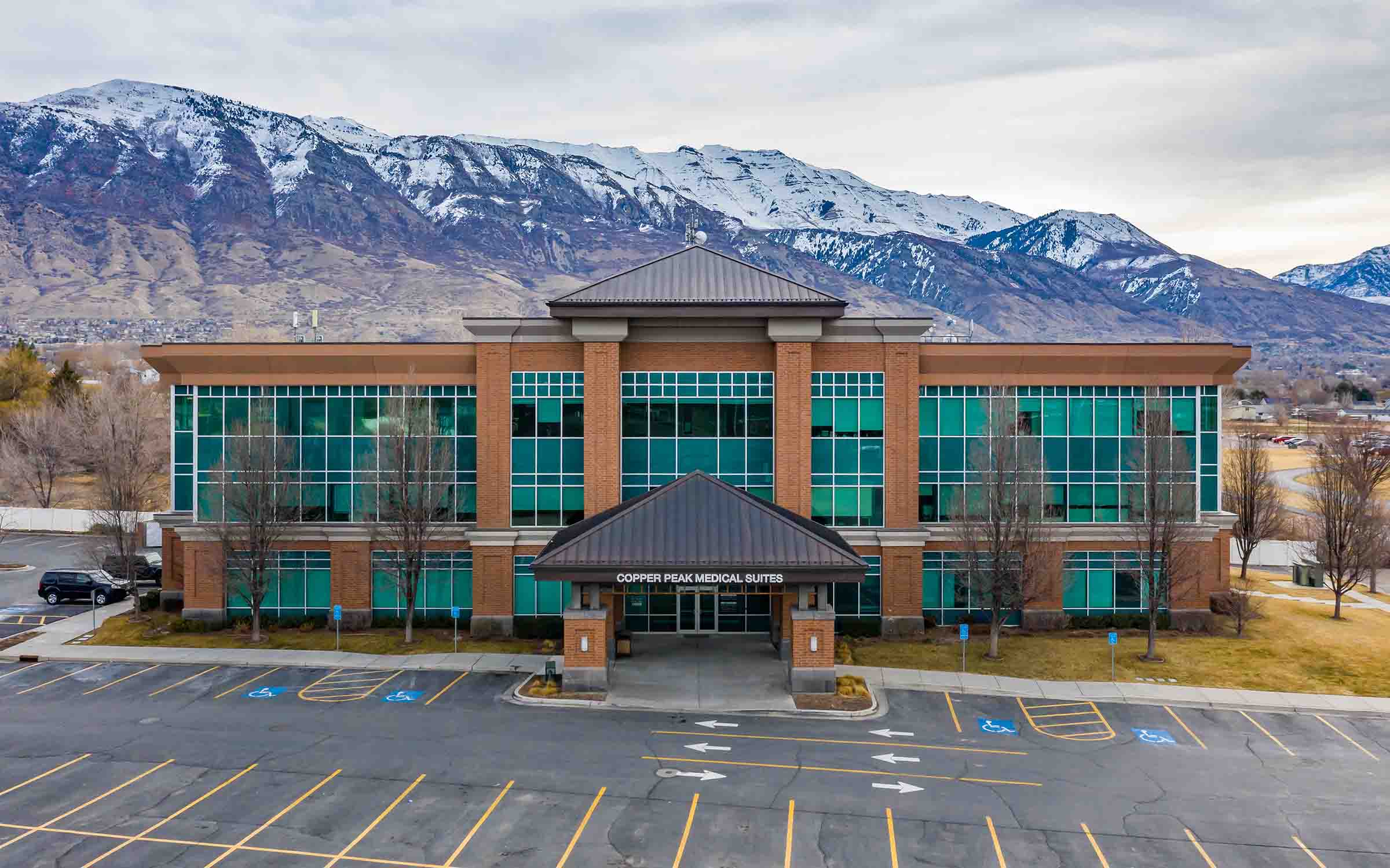 Copper Peak Medical Suites building with green windows and snow-capped mountains in the background.