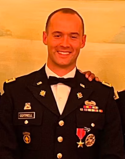 Smiling man in a decorated U.S. Army dress uniform with medals and name tag Cottrell.