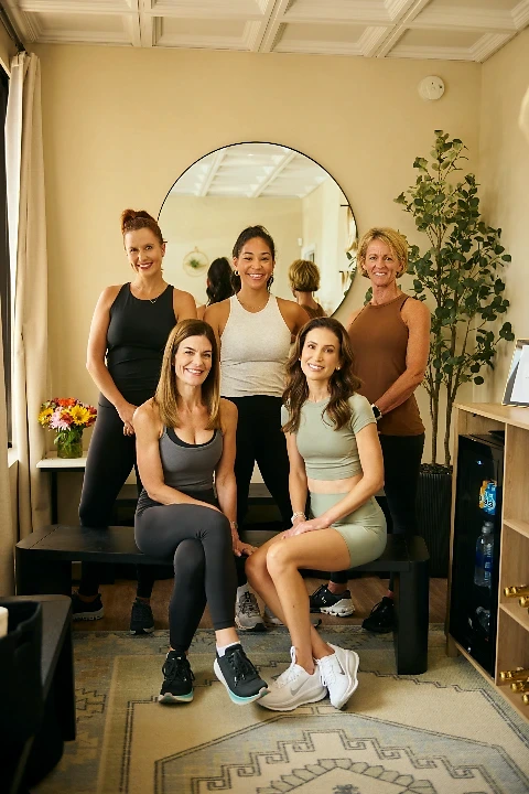 Five Club KMO members and coaches smiling together in the studio in Jacksonville, FL.