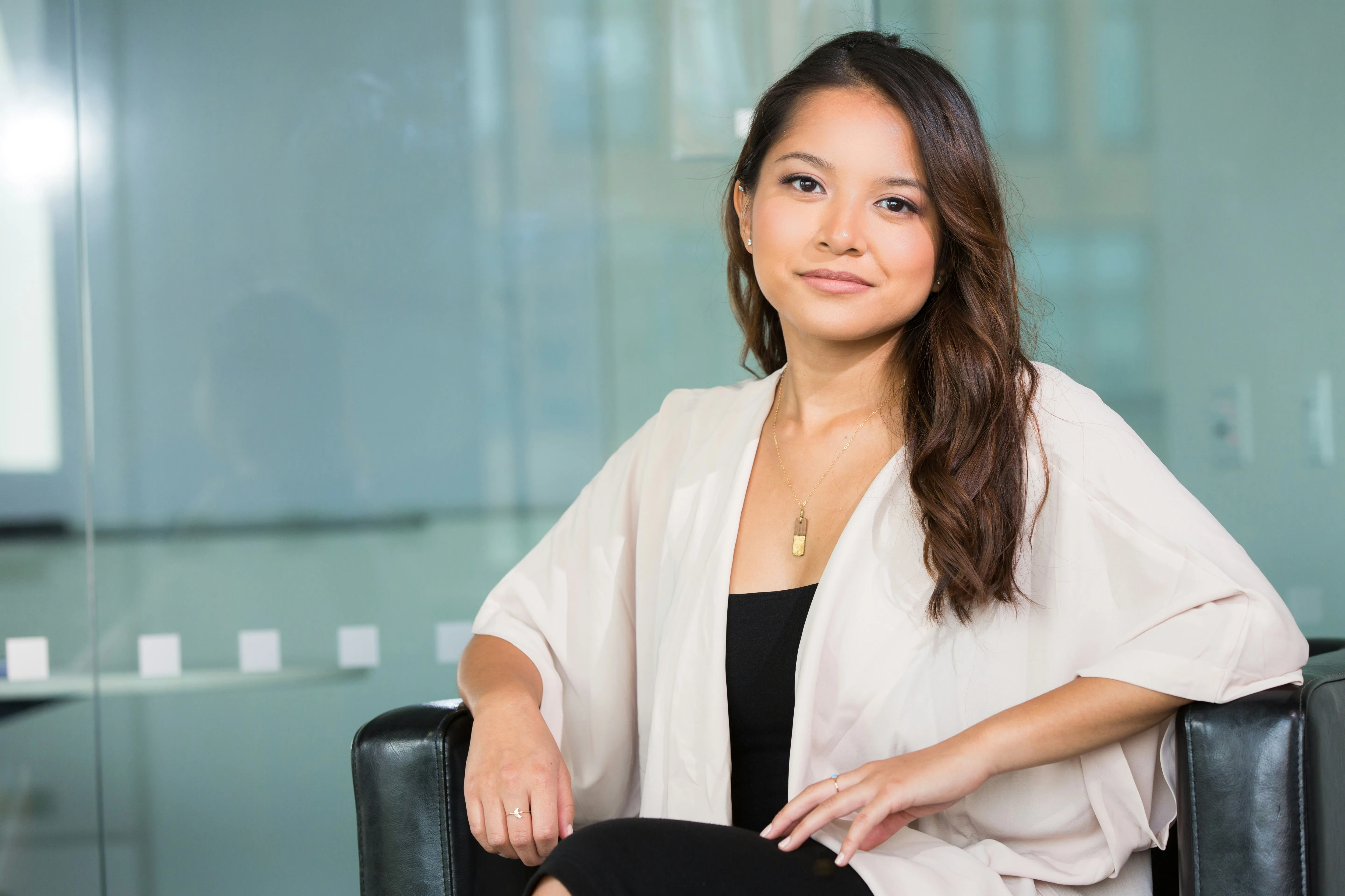 Professional woman sitting with legs crossed, smiling at the camera