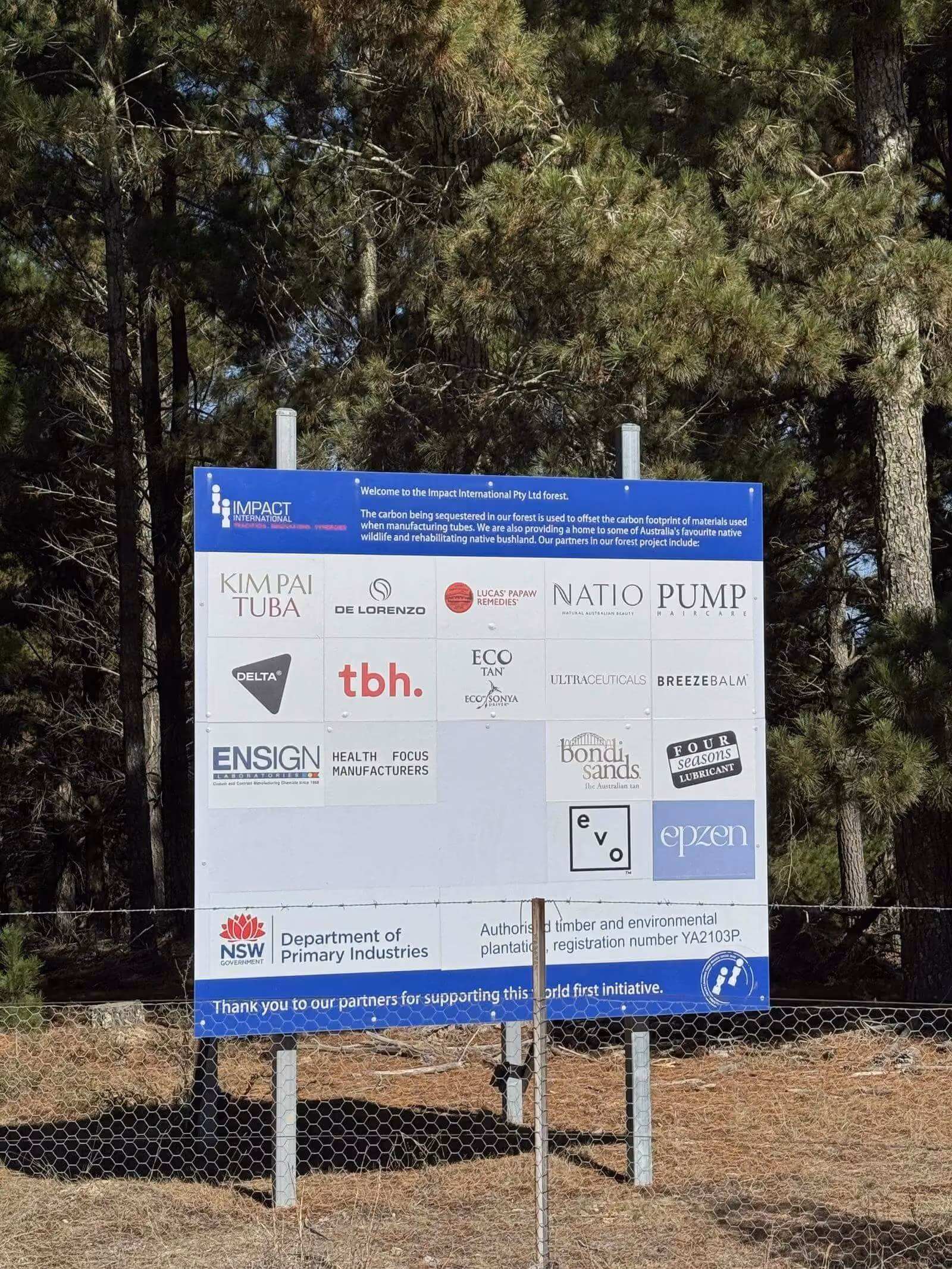 Signboard in forest listing Impact International and partners supporting carbon offset and sustainability projects.