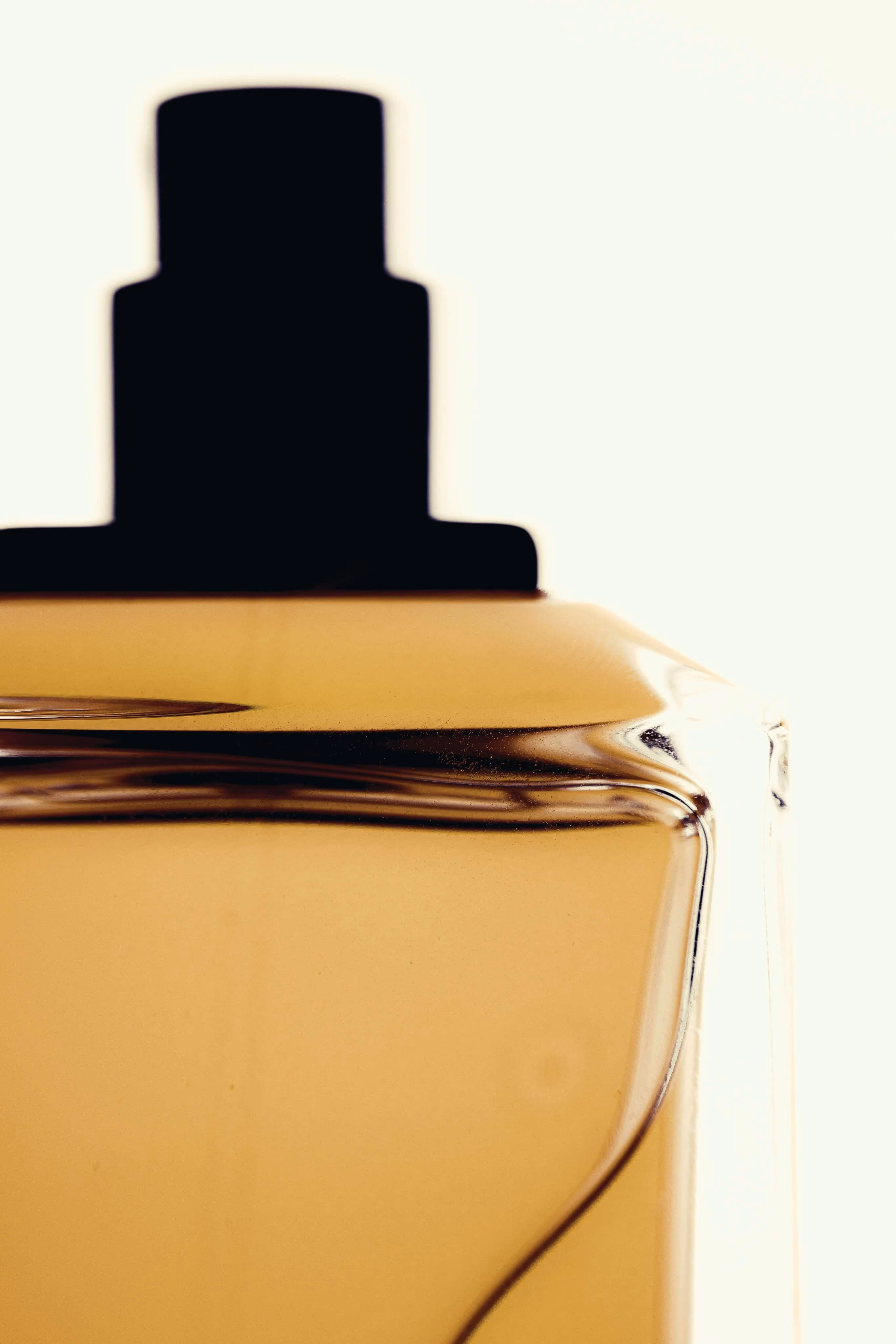 Close-up of a glass bottle filled with amber liquid and a black cap on top.