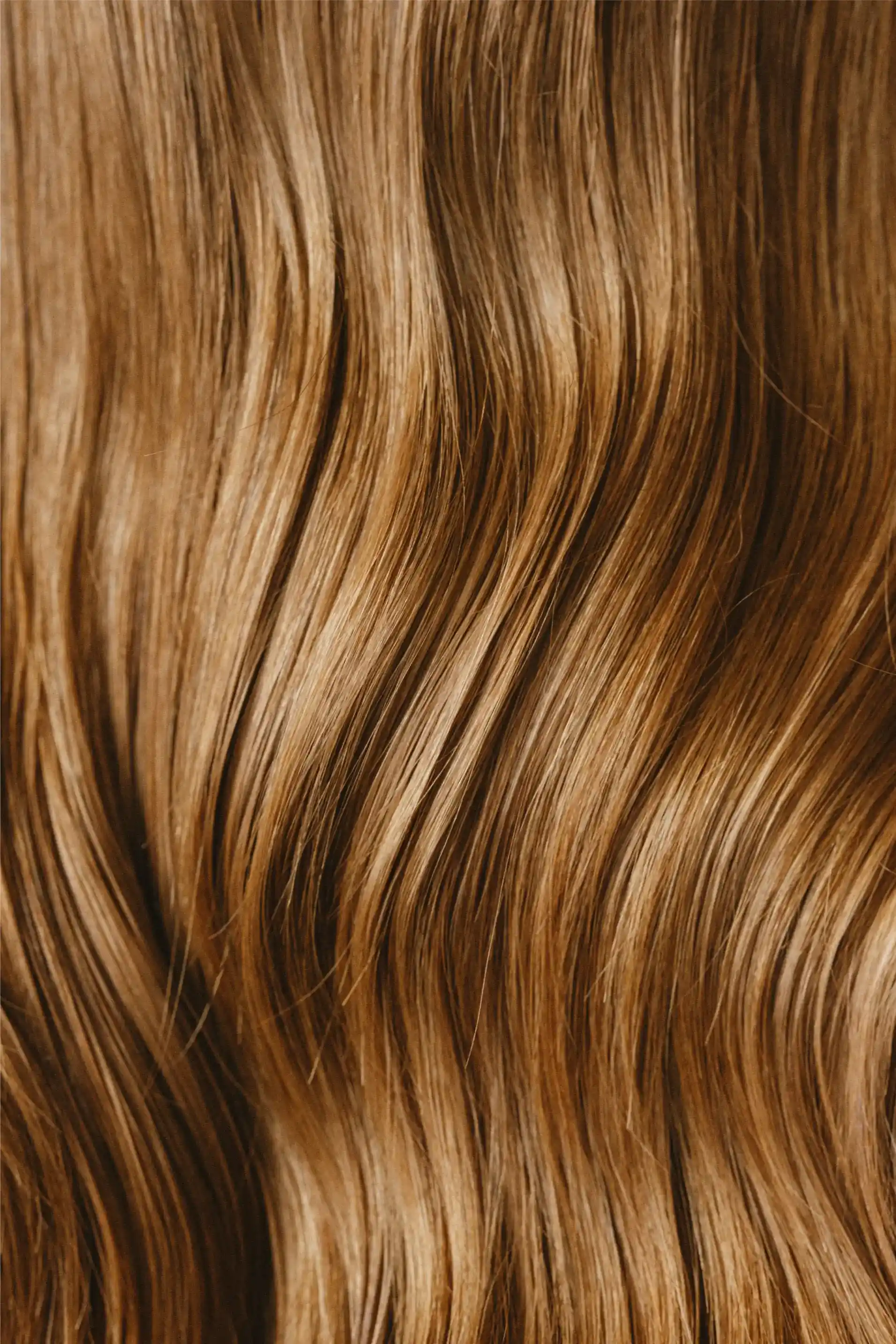 Close-up view of smooth, wavy light brown hair with natural highlights.