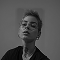 Black and white portrait of a person with short hair and glasses looking slightly upward.