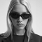 Black and white portrait of a woman wearing sunglasses with sleek hair and a serious expression.