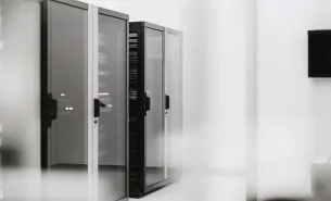 Row of server racks with glass doors in a clean technology room.