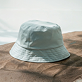 Light blue bucket hat placed on brown fabric with a soft background.