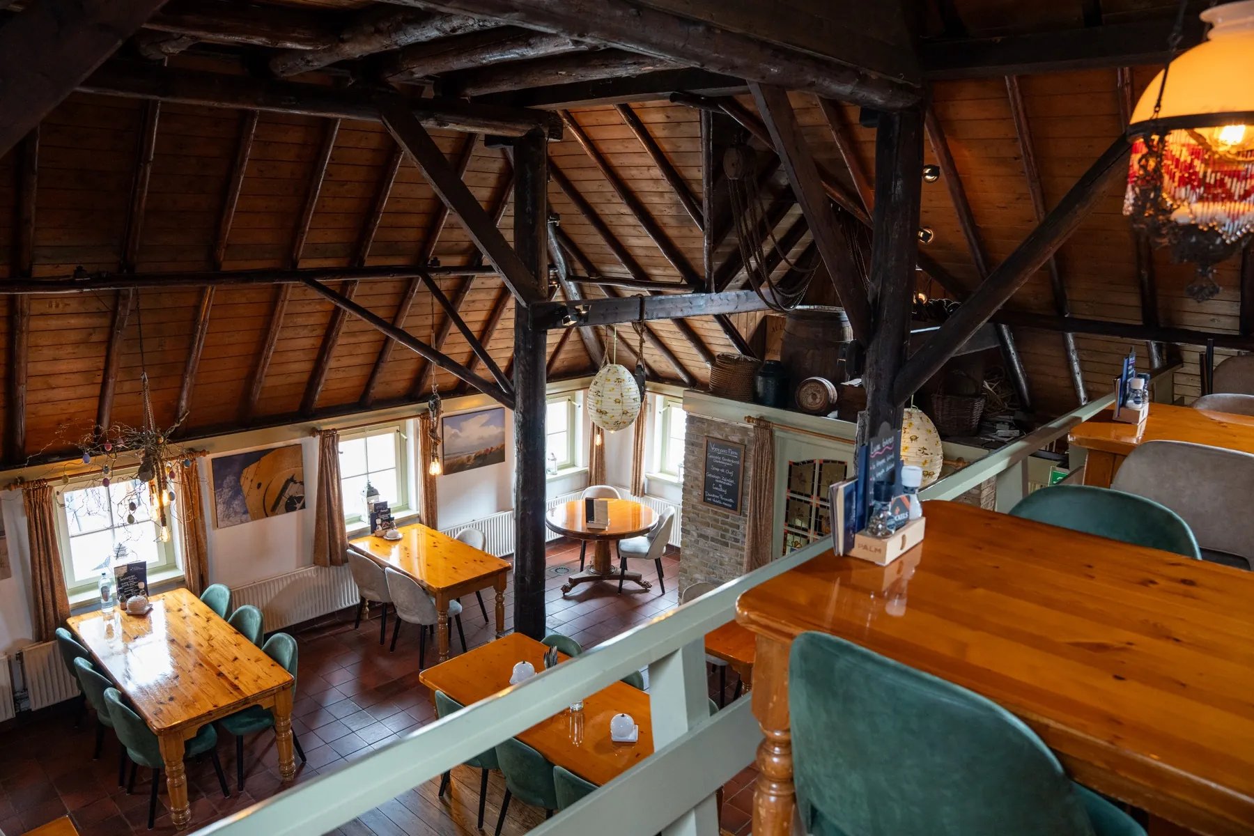 Het restaurant van boven gezien, met houten balken en groene stoelen