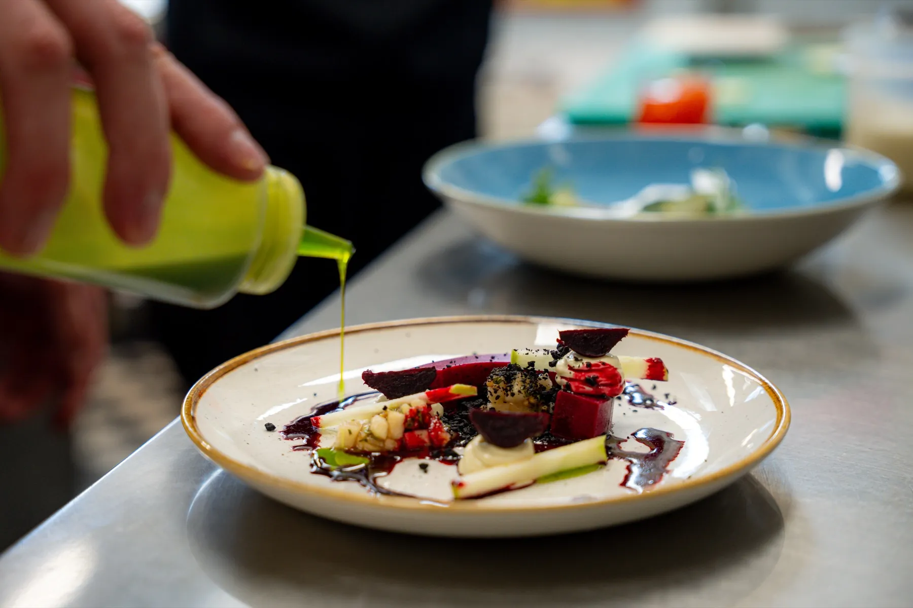 De chef maakt een gerecht af met een druppel groene olie