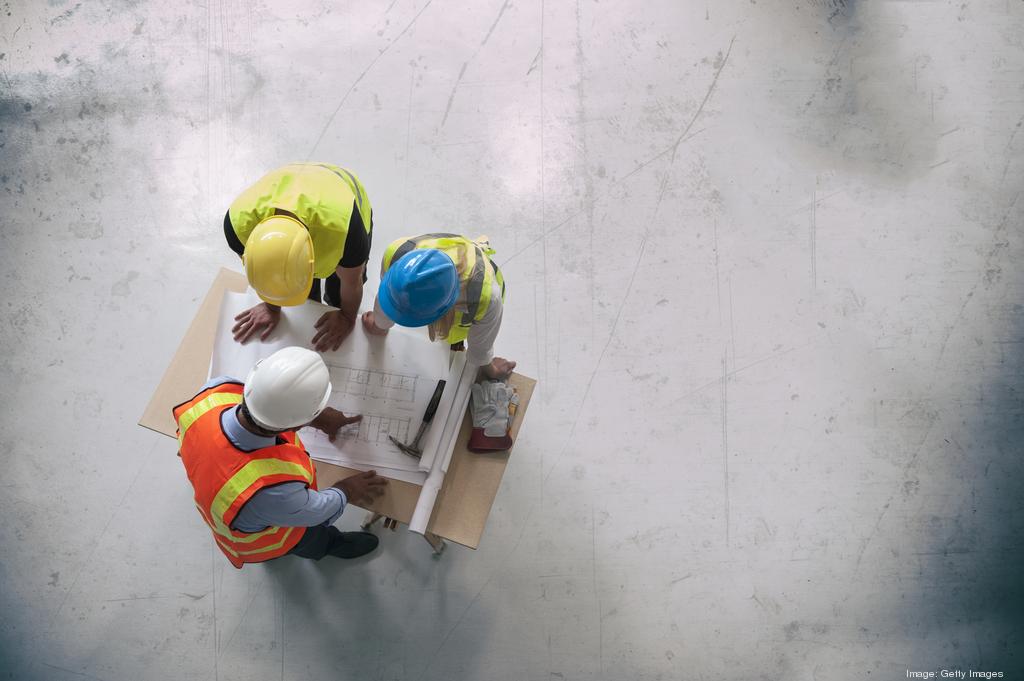 Construction team reviewing building plans, seen from above