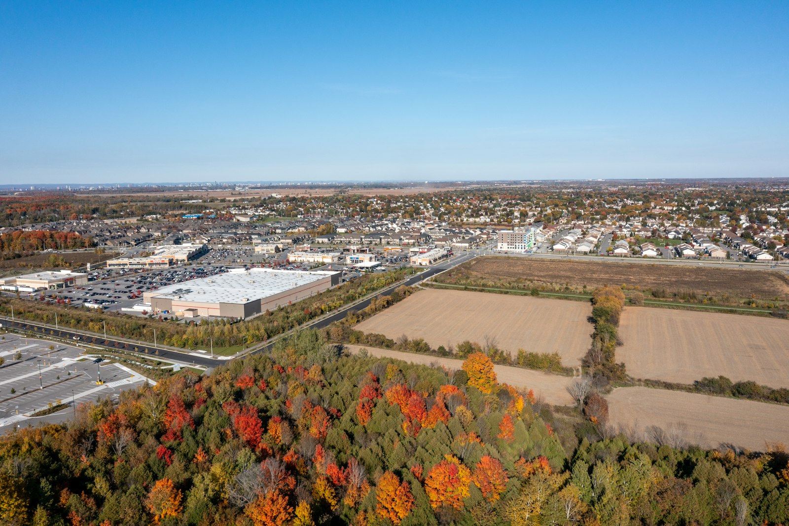 Aerial view of retail center, farmland and suburban homes