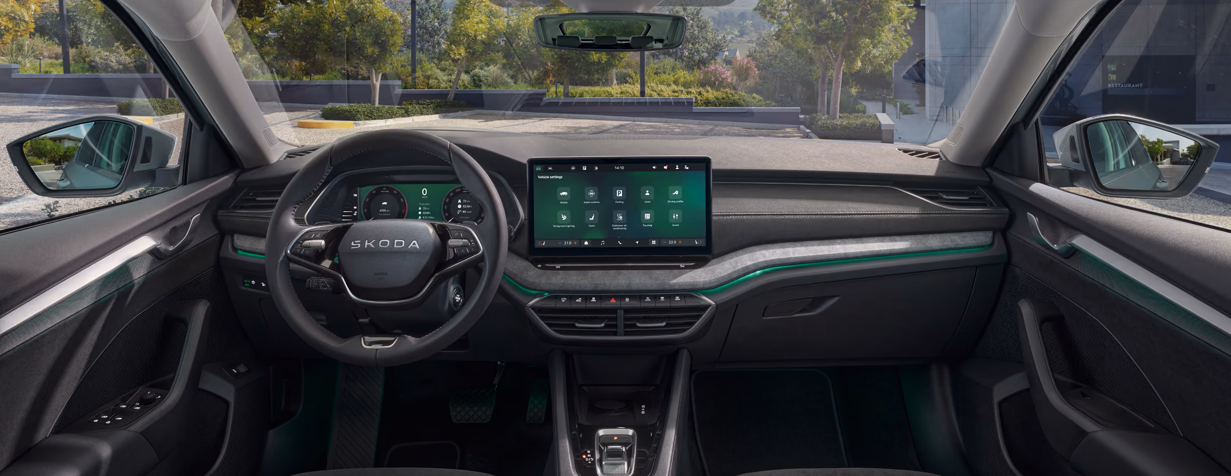Das Bild zeigt den Innenraum des Škoda Octavia 30 Jahre aus der Fahrerperspektive mit Blick auf das Armaturenbrett und durch die Frontscheibe nach draußen. Zu den zentralen Elementen gehören das Zweispeichen-Multifunktionslenkrad, das digitale Kombiinstrument sowie der freistehende Infotainment-Touchscreen. Grüne Plus-Symbole heben interaktive Bereiche hervor, darunter das Infotainment-Display, die Phonebox sowie die Ambientebeleuchtung.