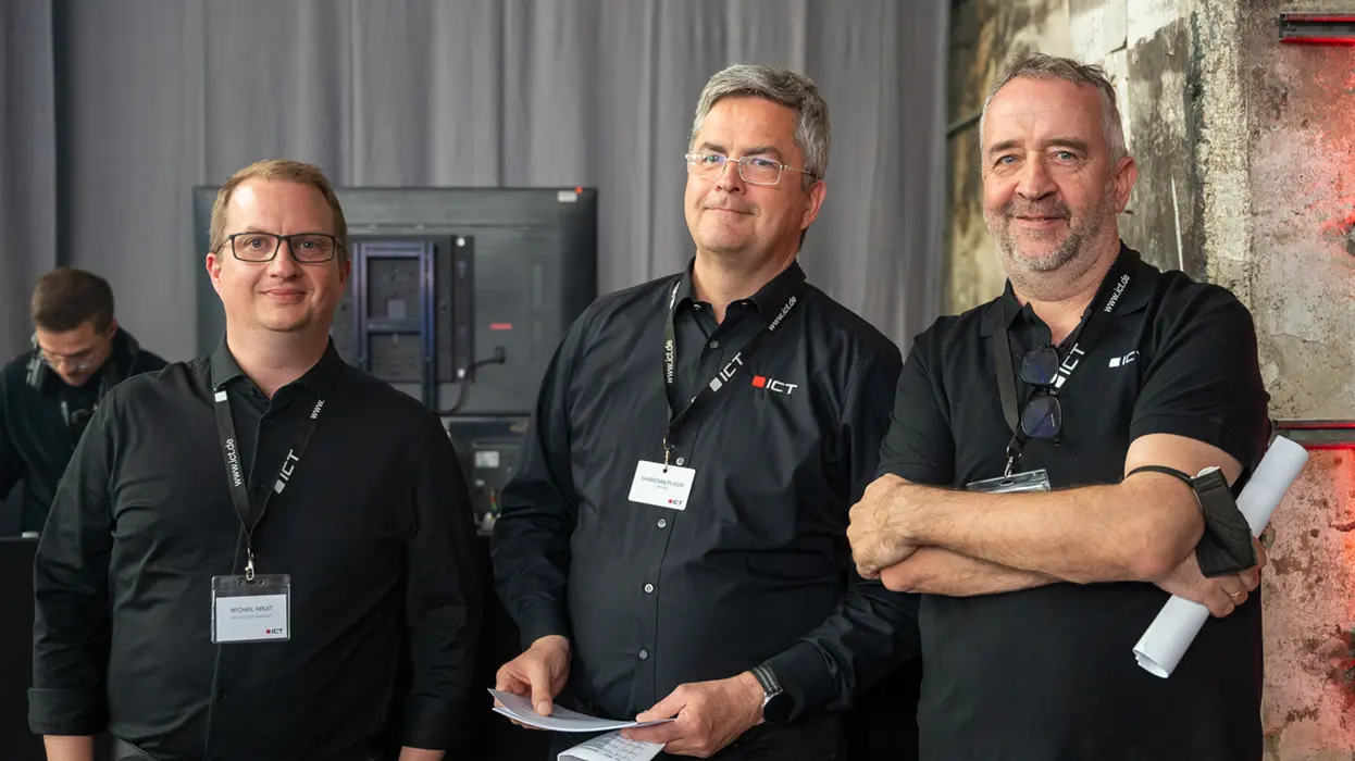 Drei Mitarbeiter des ICT-Vertriebsteams bei einer Veranstaltung.