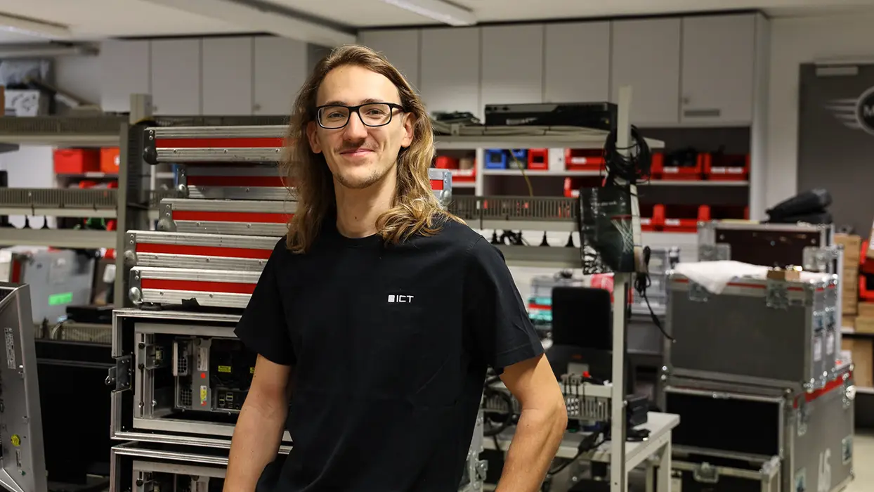 ICT-Mitarbeiter in der Werkstatt zwischen Geräten und Transportkoffern.