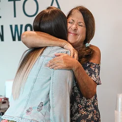 Two women warmly embracing, one with eyes closed and a content smile.