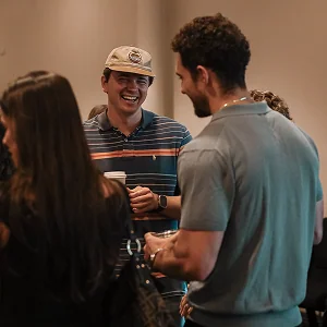 Group of young adults chatting and laughing at a social gathering indoors.