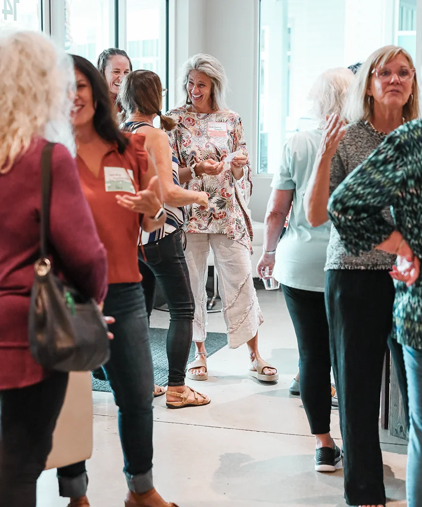 Group of women engaged in conversation at a social or networking event indoors.