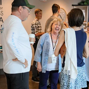 Group of people chatting and laughing at a social event indoors.