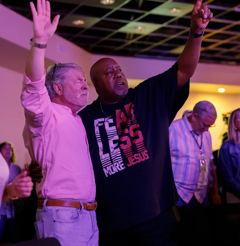 Two men worshiping with raised hands during a church service.