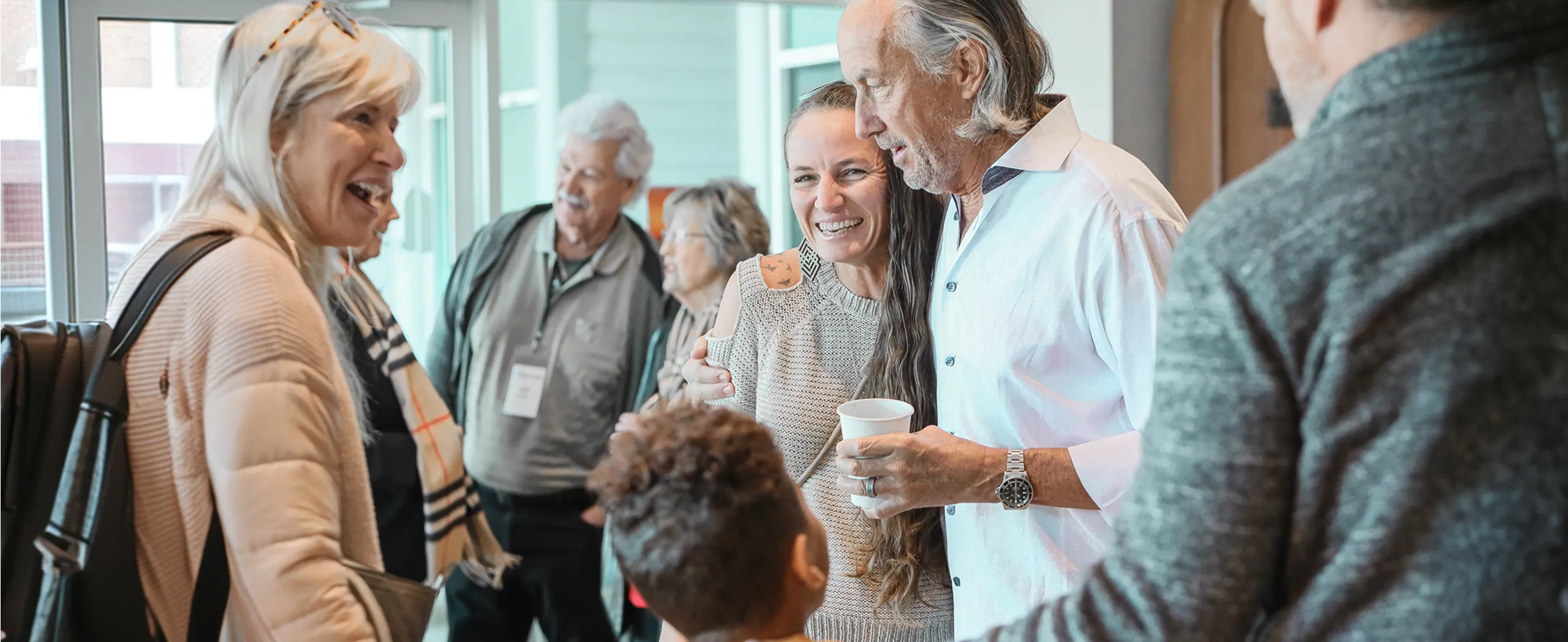 Group of diverse people smiling and laughing together indoors at a social gathering.