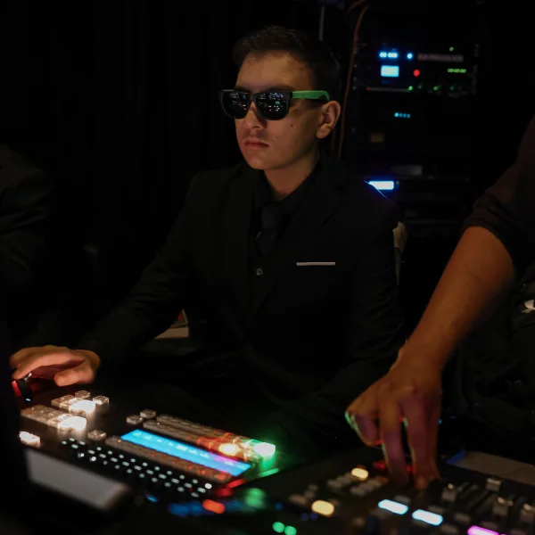 Man operating a lighting control panel, representing The Sanctuary Media volunteer team.