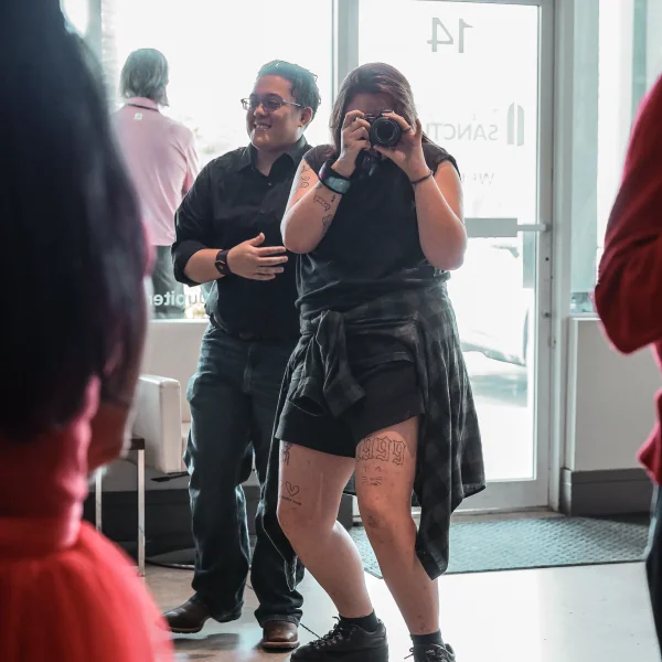 Woman taking a photo with a camera, representing The Sanctuary Marketing & Communications volunteer team.