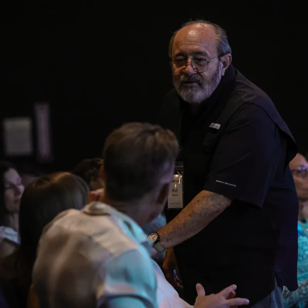 Man speaking to an audience at an event, representing The Sanctuary Usher volunteer team.