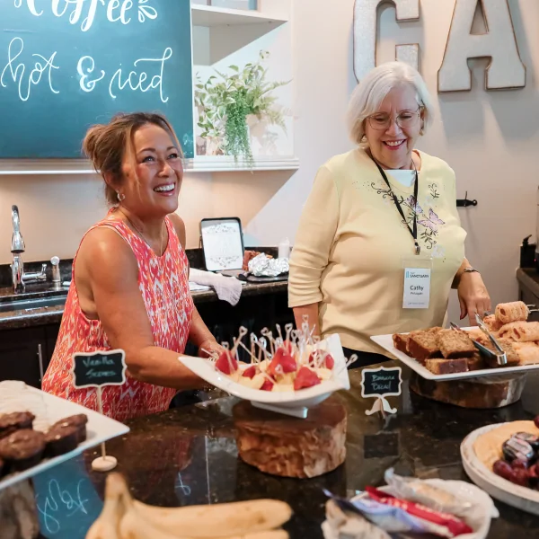 Women serving desserts at a cafe, representing The Sanctuary Cafe volunteer team.