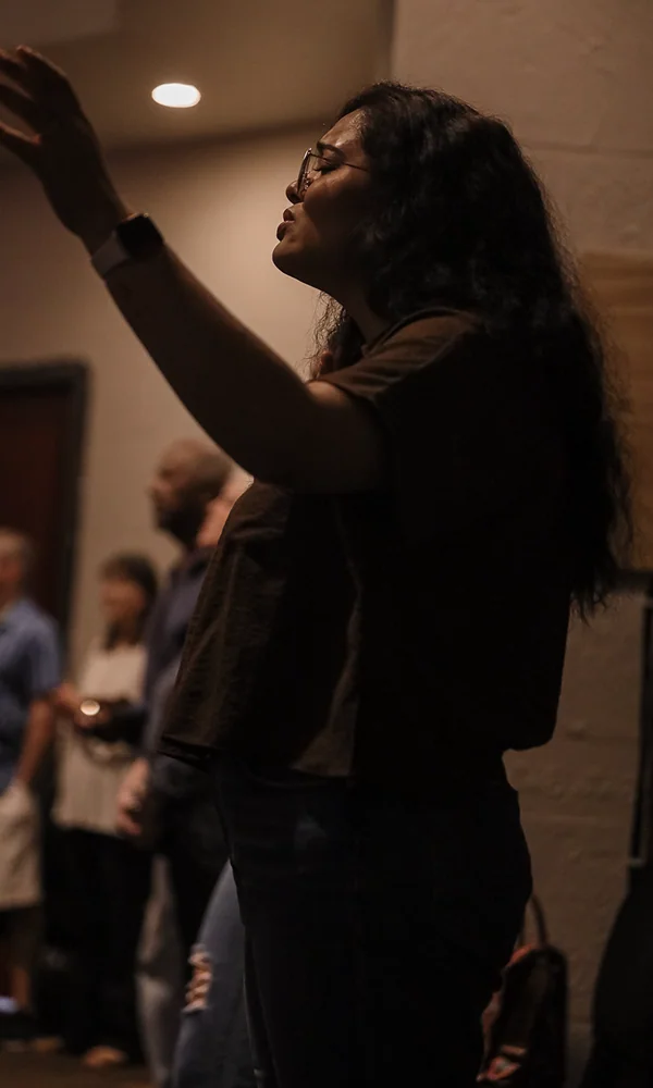 Woman raising her hand in worship during a church service.