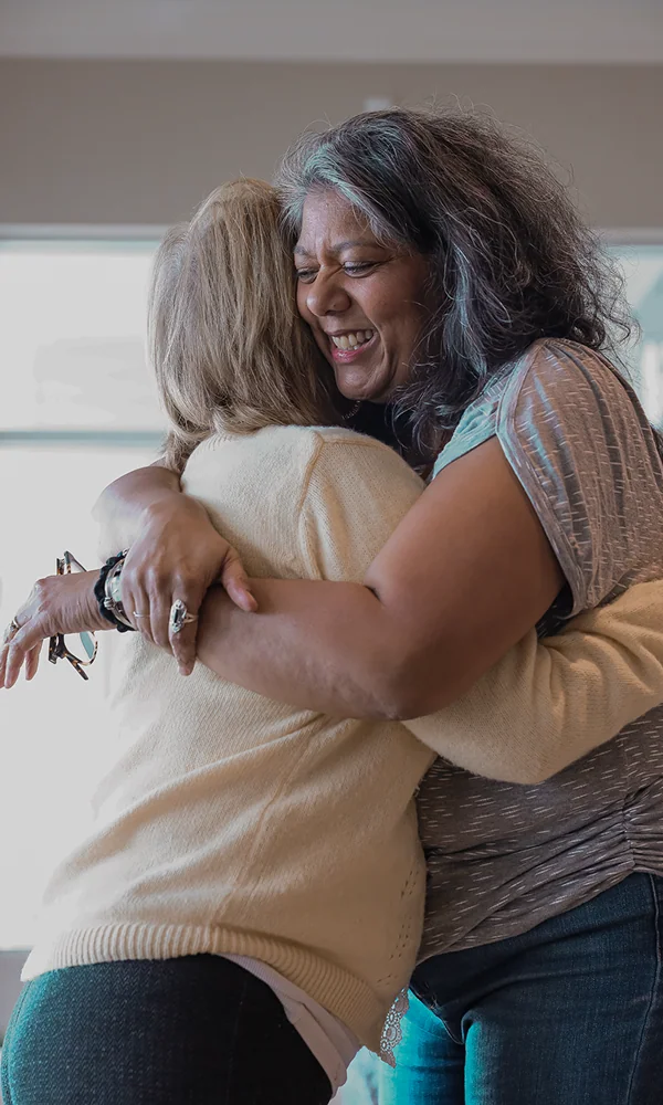 Two women hugging warmly at a church community gathering.