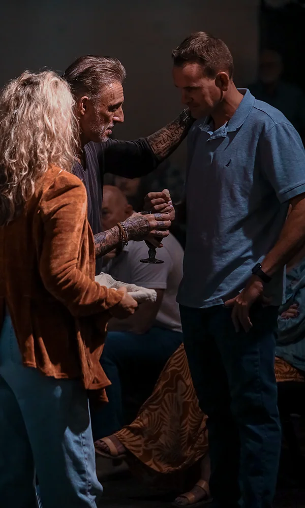 Man with tattoos handing a card to another person at a church event.