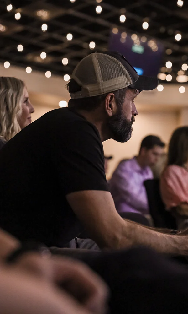 Man wearing a cap listening at a church event.