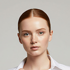 Portrait of a young woman with red hair tied back, wearing a white collared shirt against a light gray background.