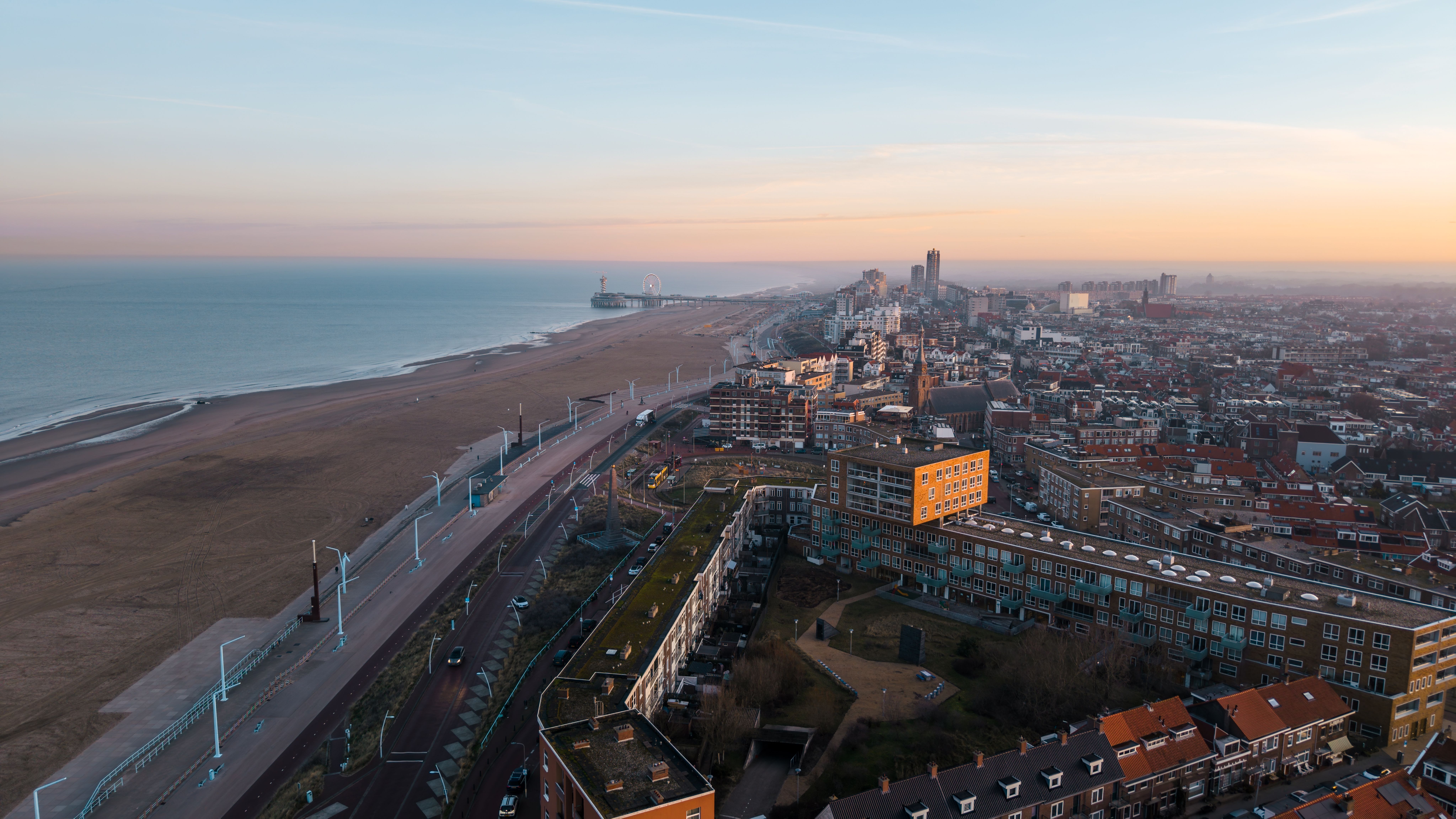 Kitesurfers riding waves off Scheveningen Beach, Netherlands — popular kitesurfing spot with strong winds, sandy shoreline and city promenade.