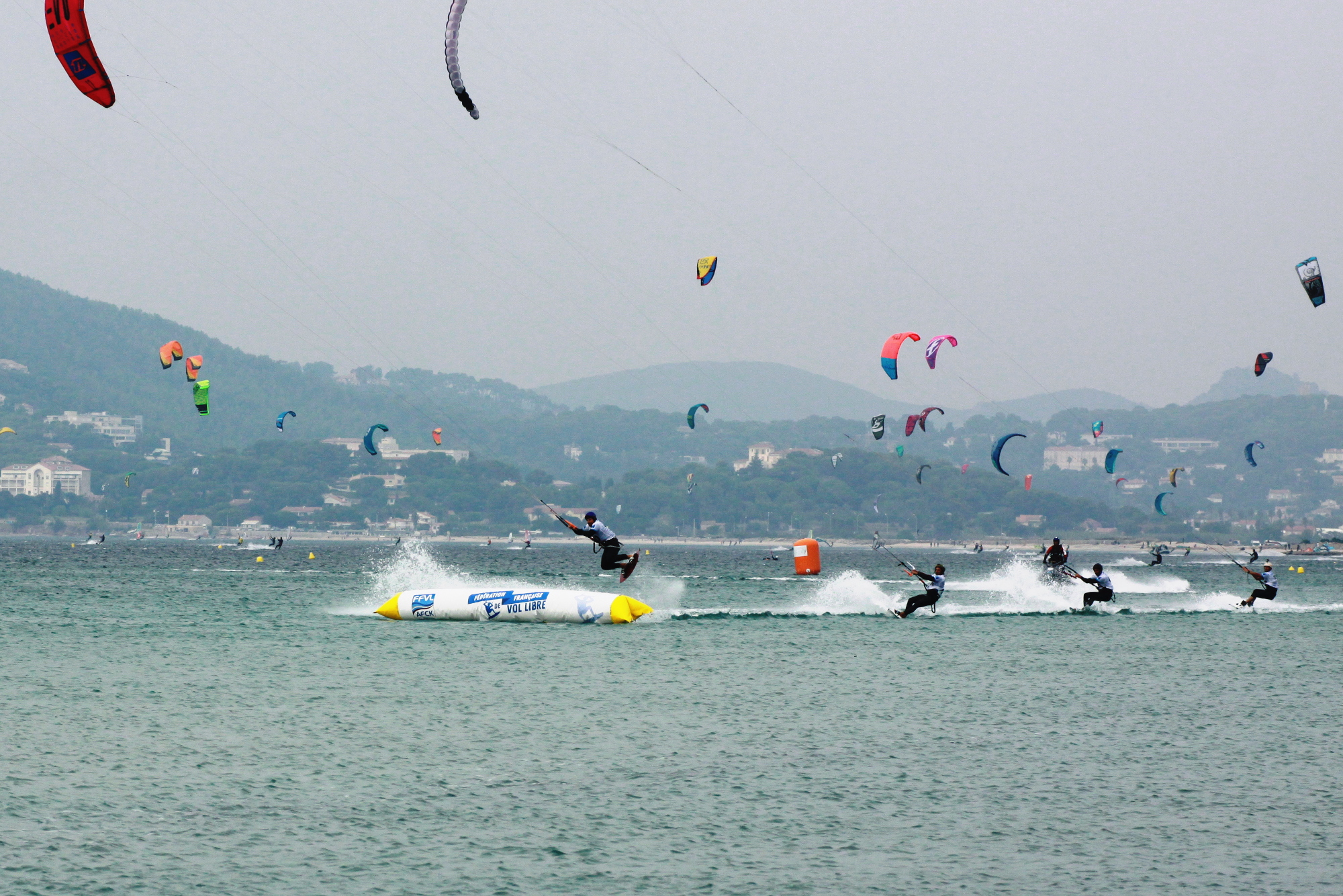 Kitesurf spot Hyères — Almanarre, France: kitesurfers with colorful kites over turquoise Mediterranean, wide sandy beach and steady wind