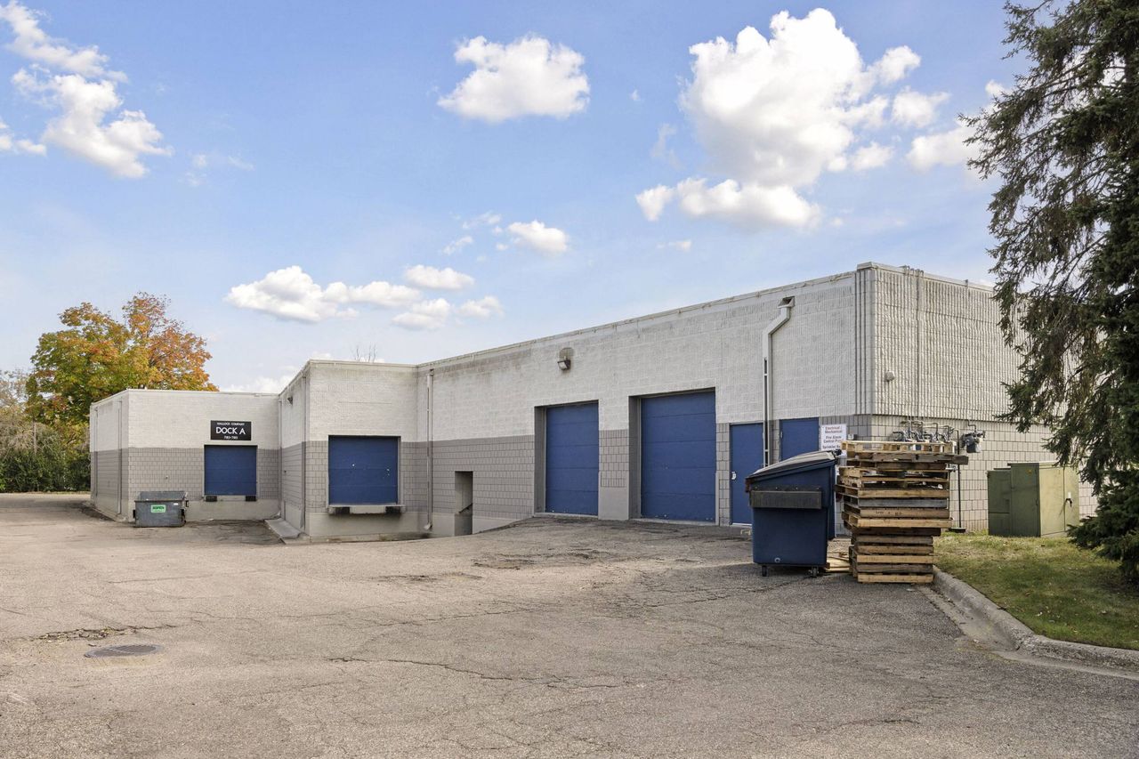 Rear elevation with blue overhead loading doors and a waste container