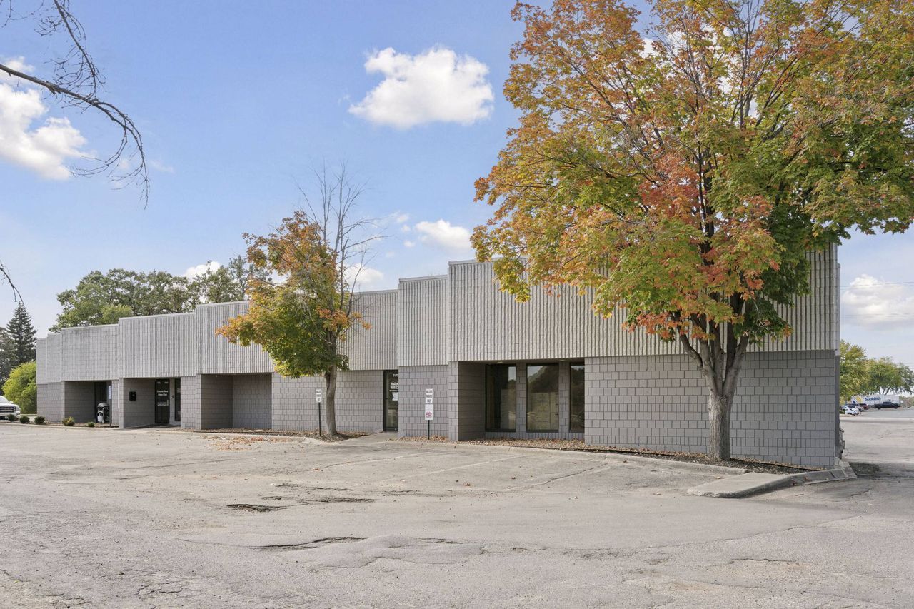 Light grey block wing with recessed entries seen past autumn maples