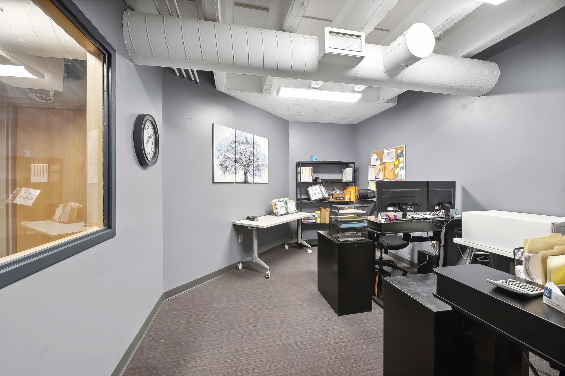 Work room with grey-blue walls, desks and an interior window
