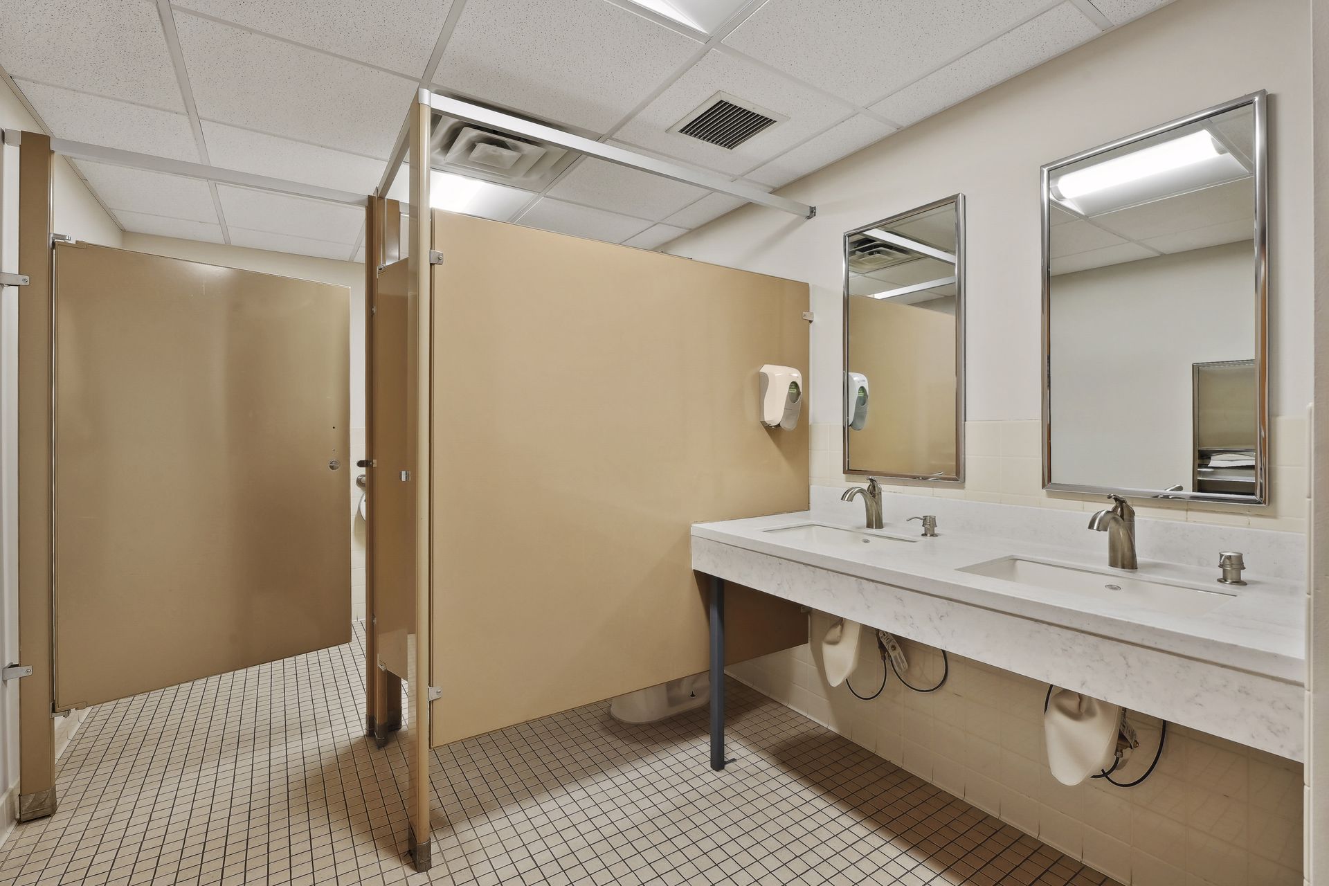 Common restroom with tan stall partitions and a double vanity