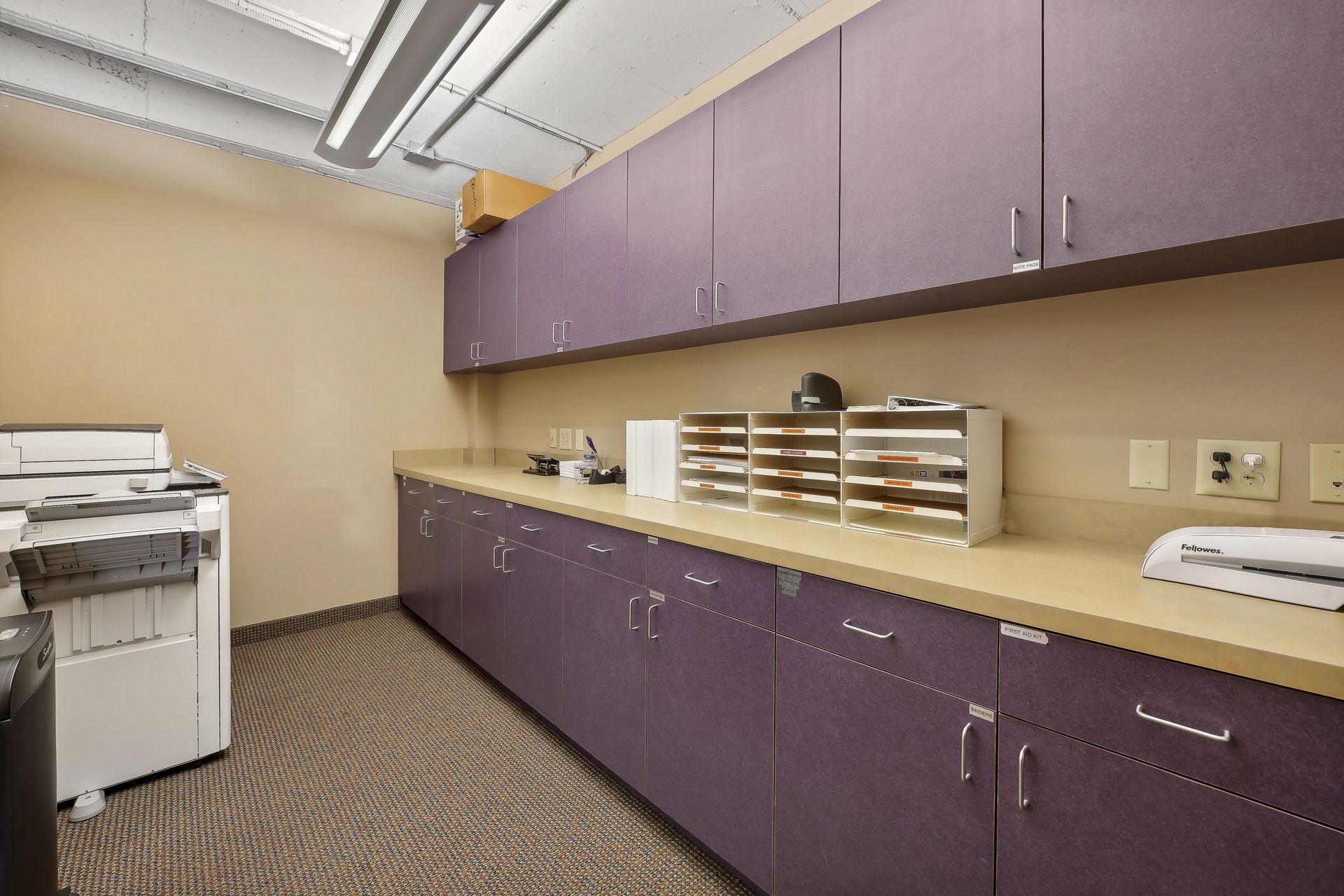 Mail and copy room with purple cabinetry, a copier and wall-mounted mail sorters