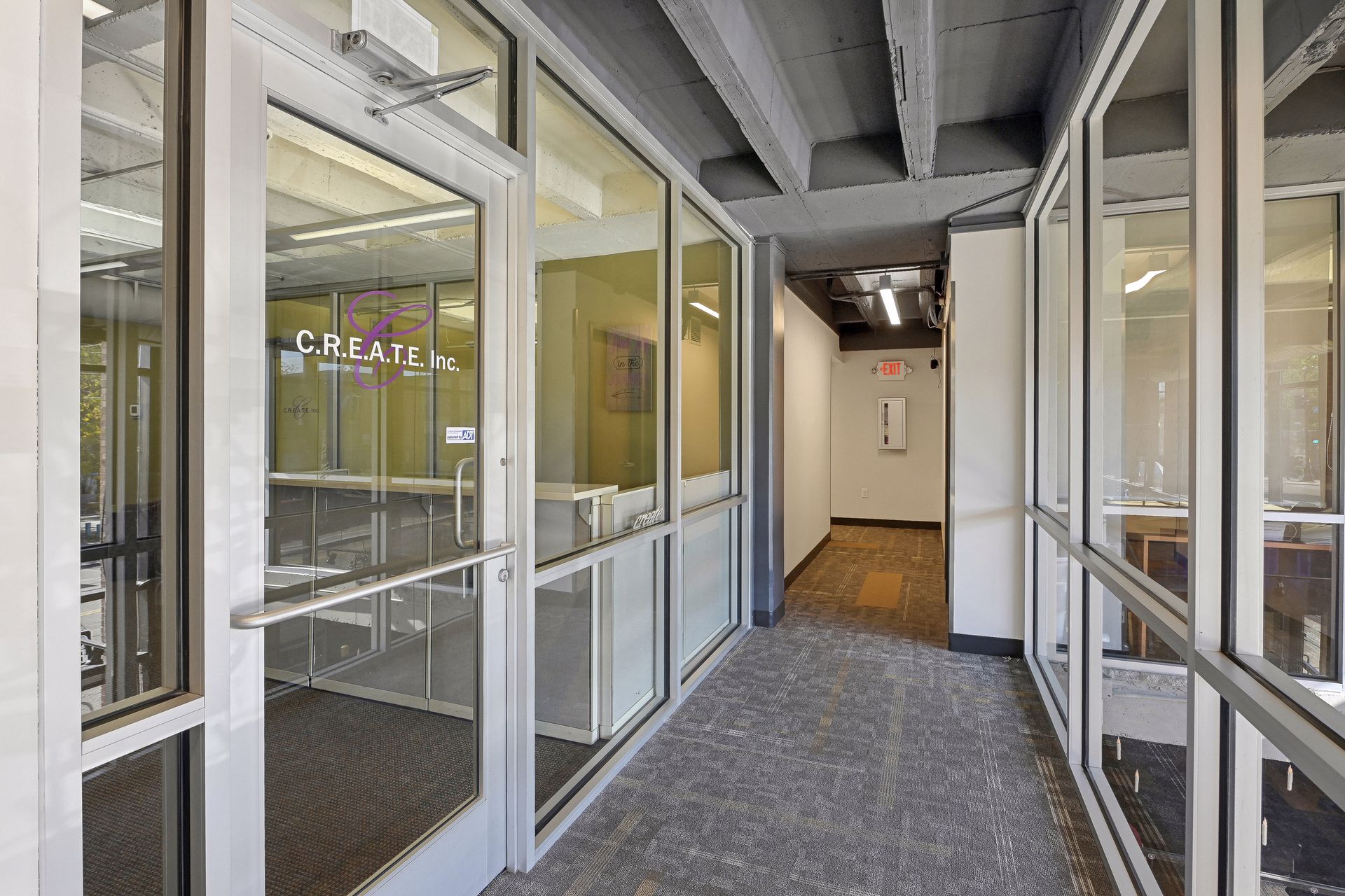 Corridor at a suite entrance with glazed doors and offices along one side