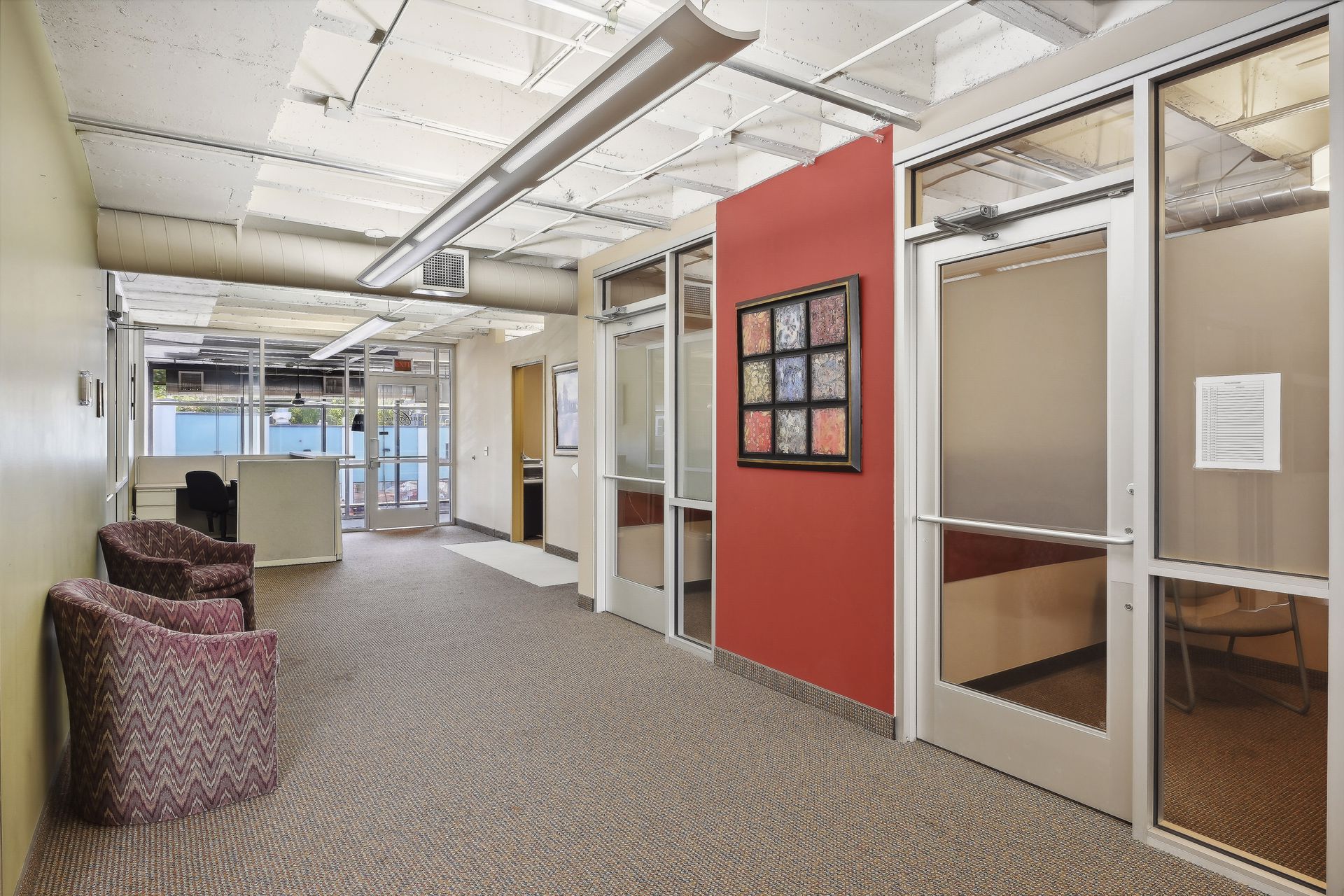 Corridor with glass-fronted conference rooms and lounge seating