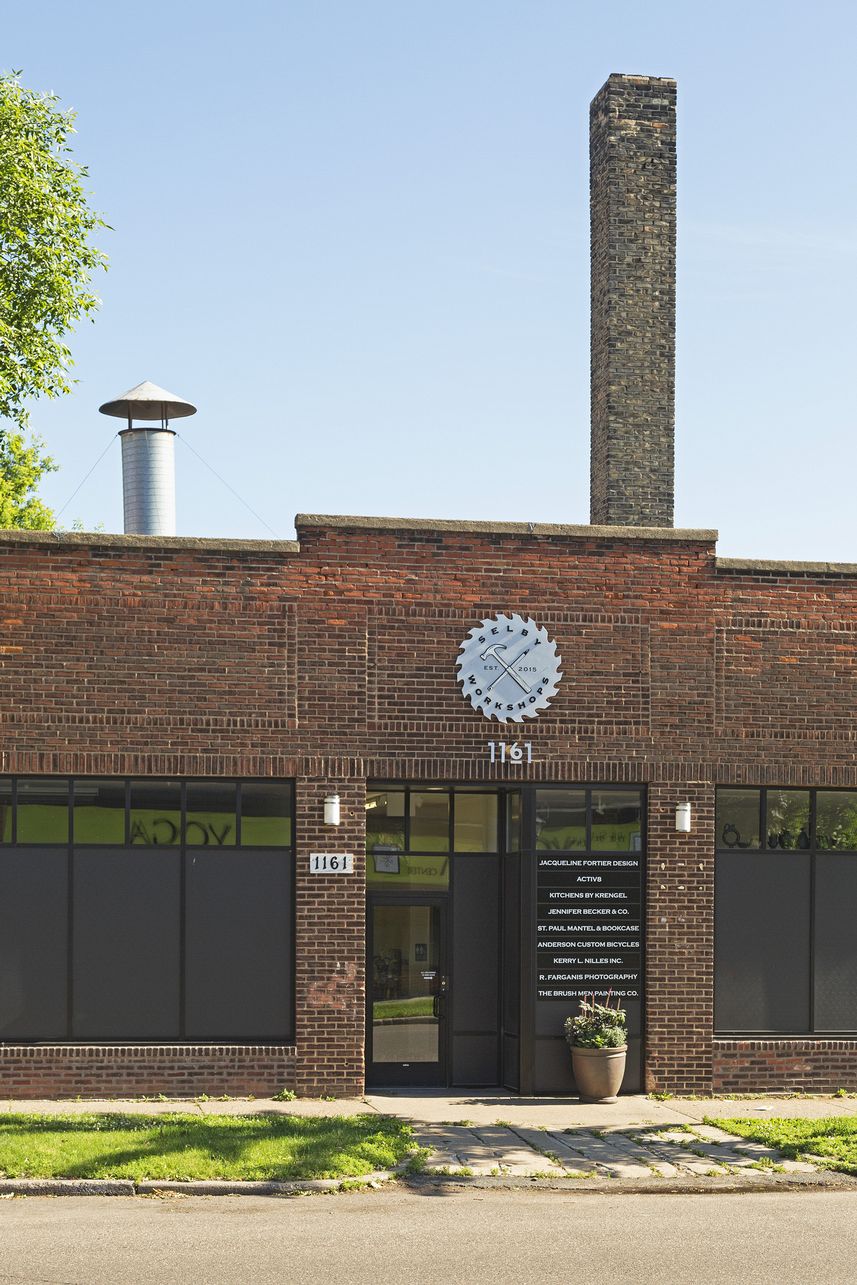 Building entrance with a circular saw-blade sign, the numerals 1161 in metal and a glass door