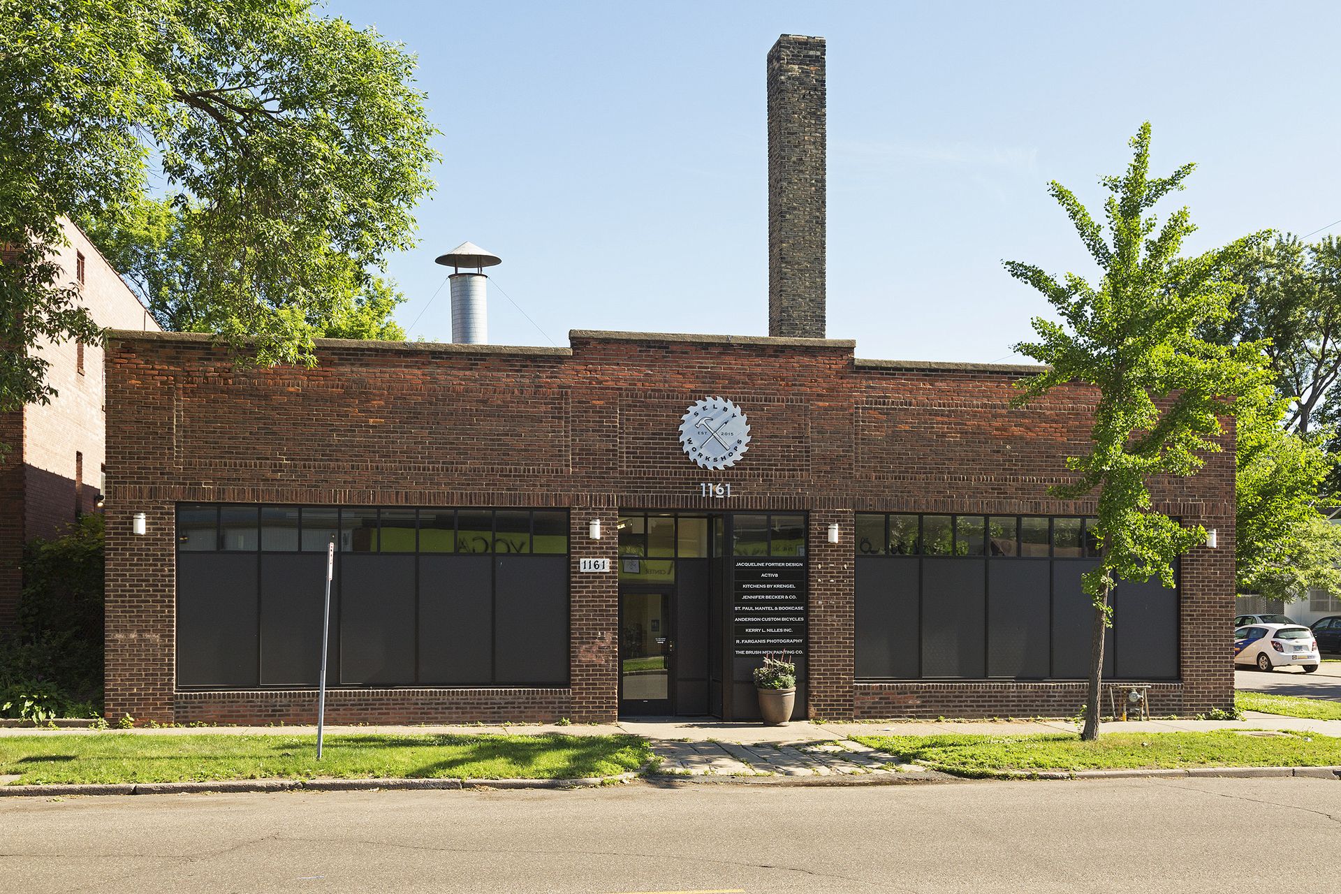 Straight-on view of the brick facade with two bands of dark windows flanking a central glass entrance